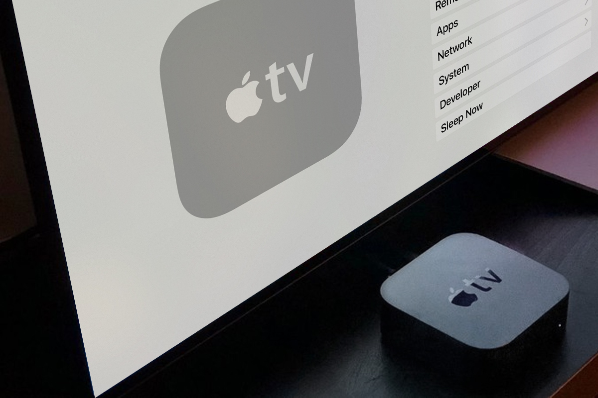 AppleTV-Streamingsbox neben einem Bildschirm mit AppleTV Settings
