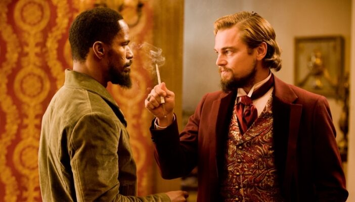 Ein weisser reicher Mann steht mit einer Zigarette in der Hand vor einem afroamerikanischen Sklaven