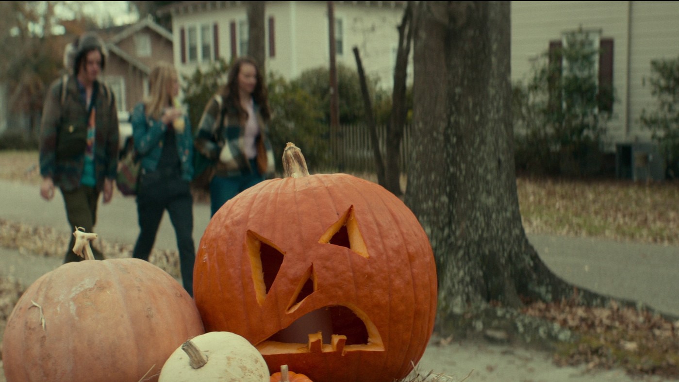 Ein Halloween-Kürbis vor einer Gruppe junger Leute.